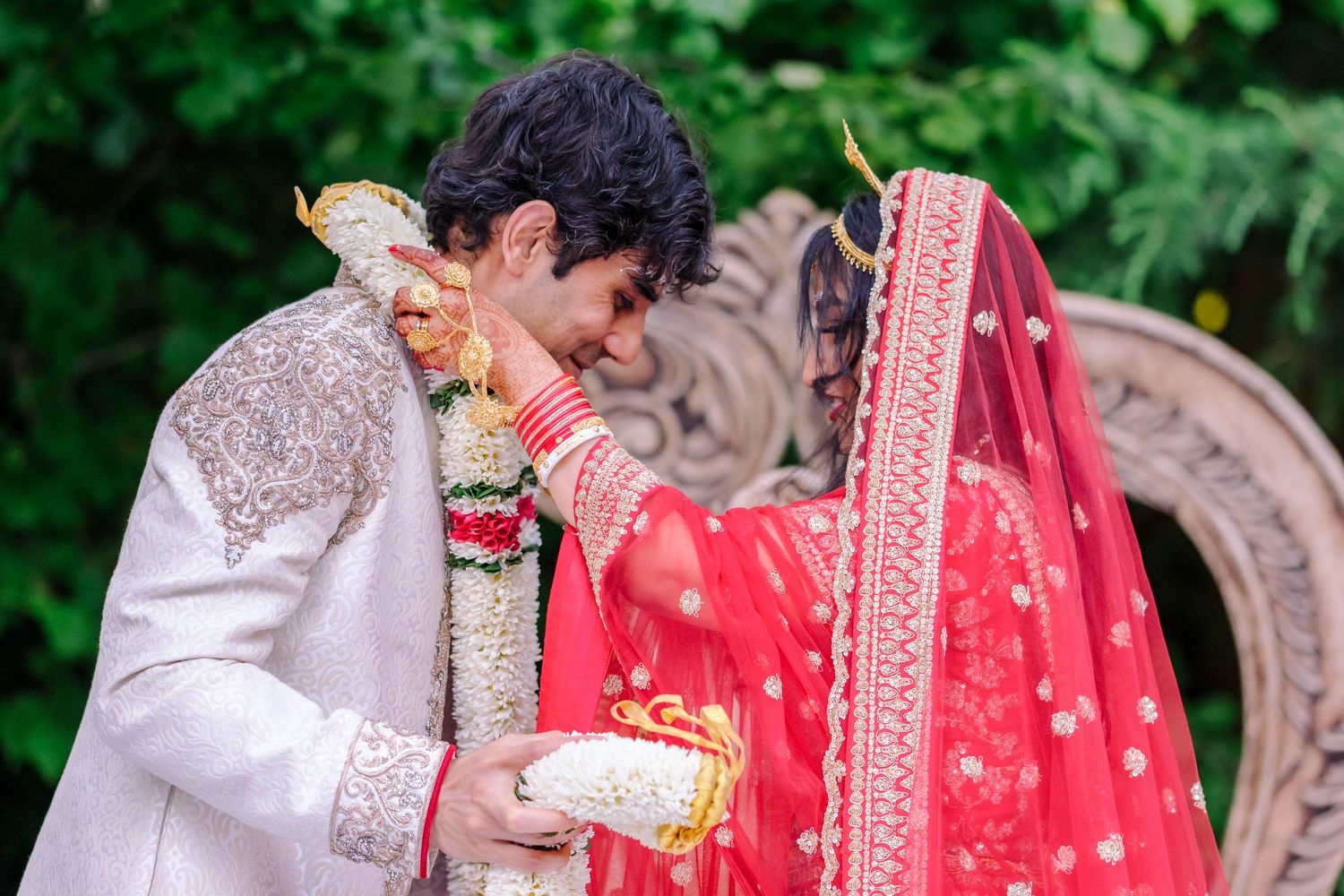 Traditional Indian wedding ceremony with vibrant red and gold attire under decorative mandap.