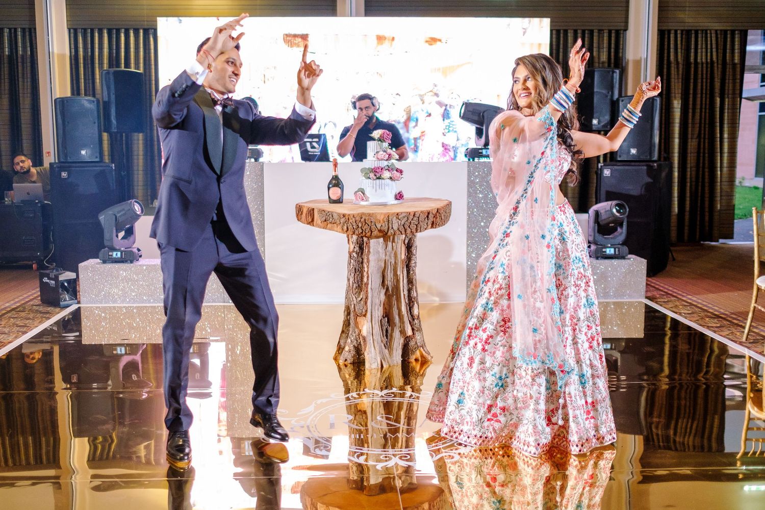 Dancers in formal attire perform traditional ballroom steps on a polished wooden dance floor at an elegant event.