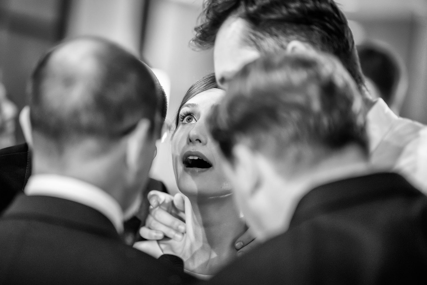 Monochrome wedding photography showing guests engaged in conversation at a reception.