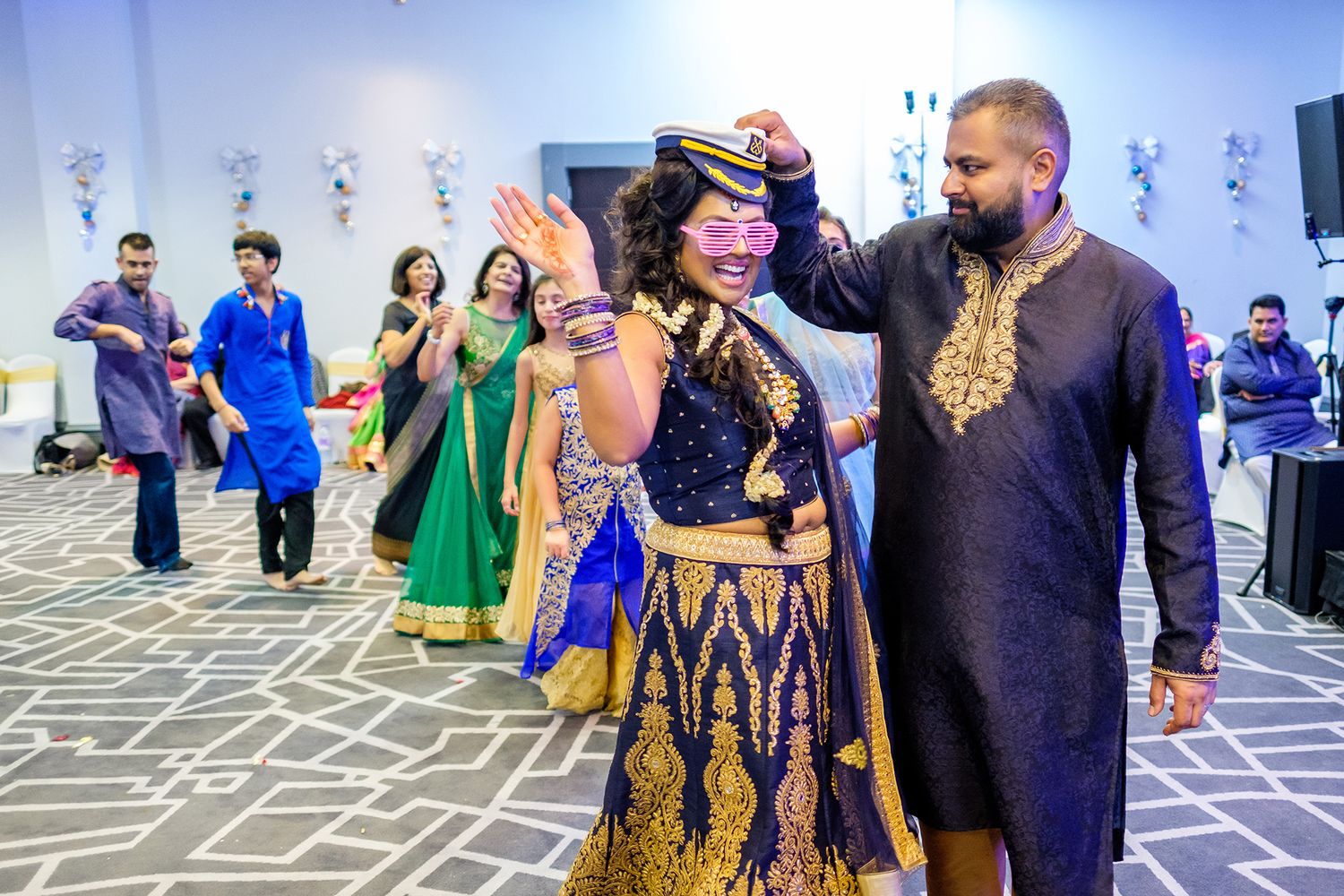 Guests in traditional Indian formal wear gather for a celebration in an elegantly decorated ballroom.