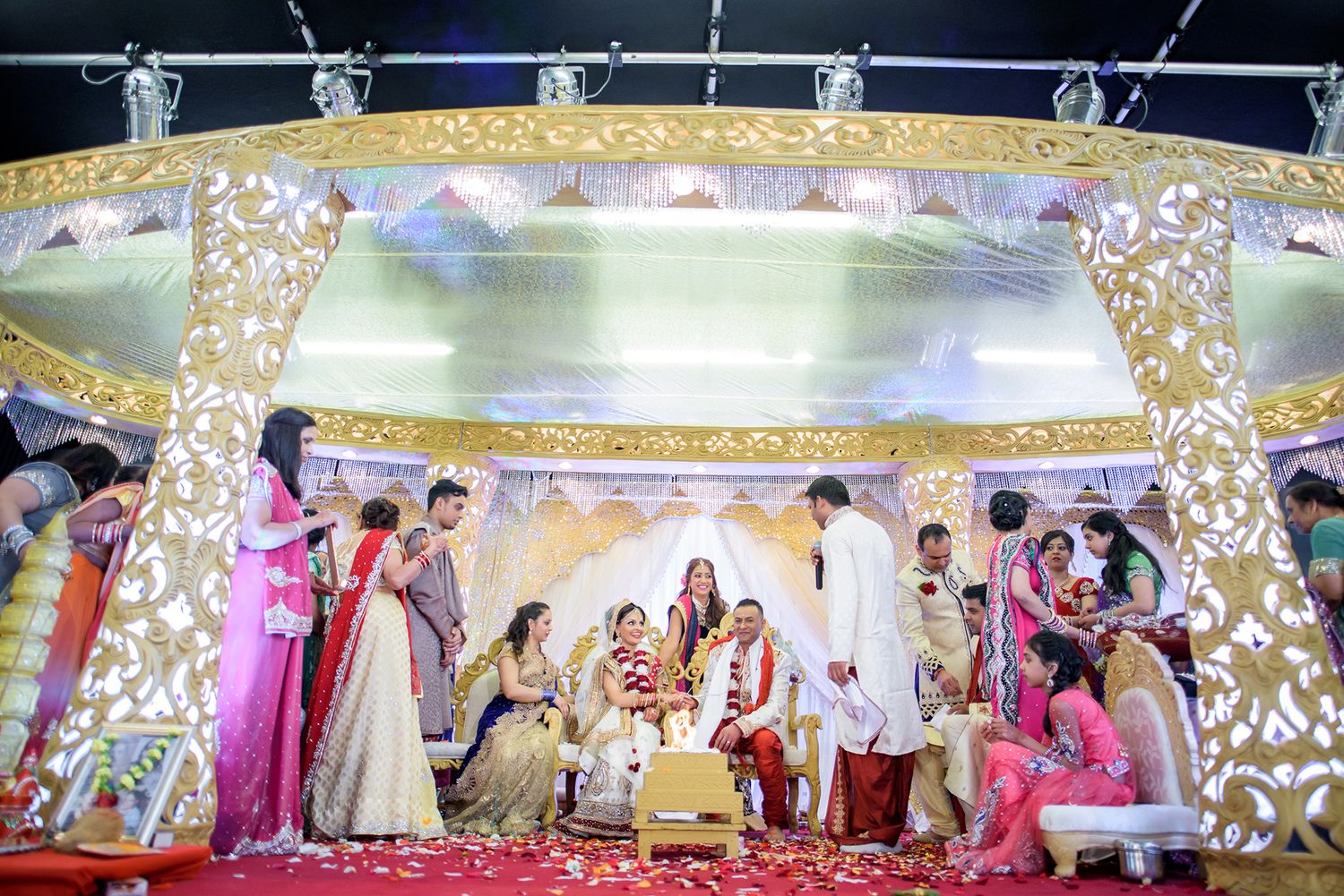 Wide-angle shot of elaborately decorated Indian wedding venue with ornate ceiling details.