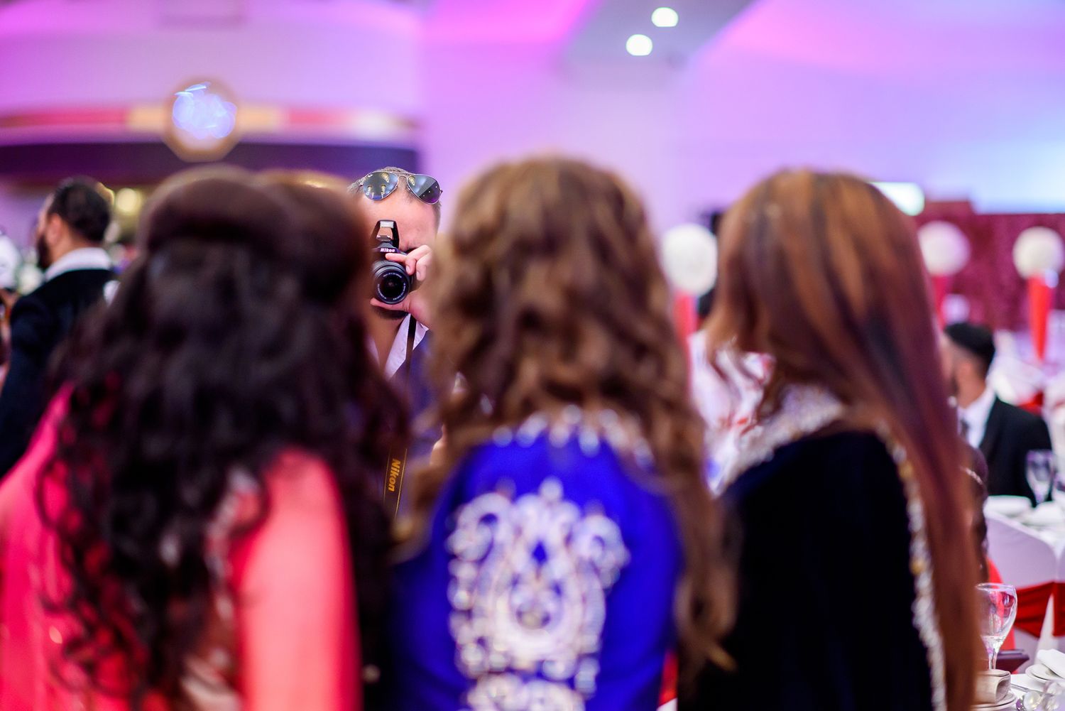 Colorful celebration at a traditional Indian wedding with festive pink lighting and decorative elements.