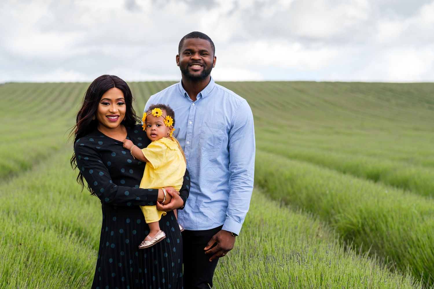 Happy family spending time together in a bright green field during a sunny outdoor photo session.