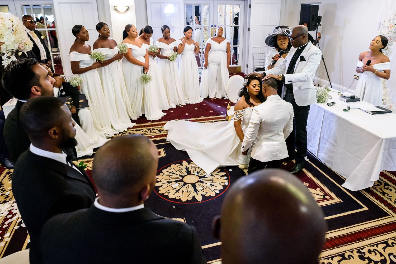 Multiple guests gather at a formal event to pray and share a meal in a traditional Islamic setting.