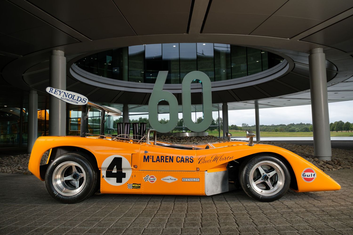Collection of orange McLaren racing cars displayed in a modern showroom setting.