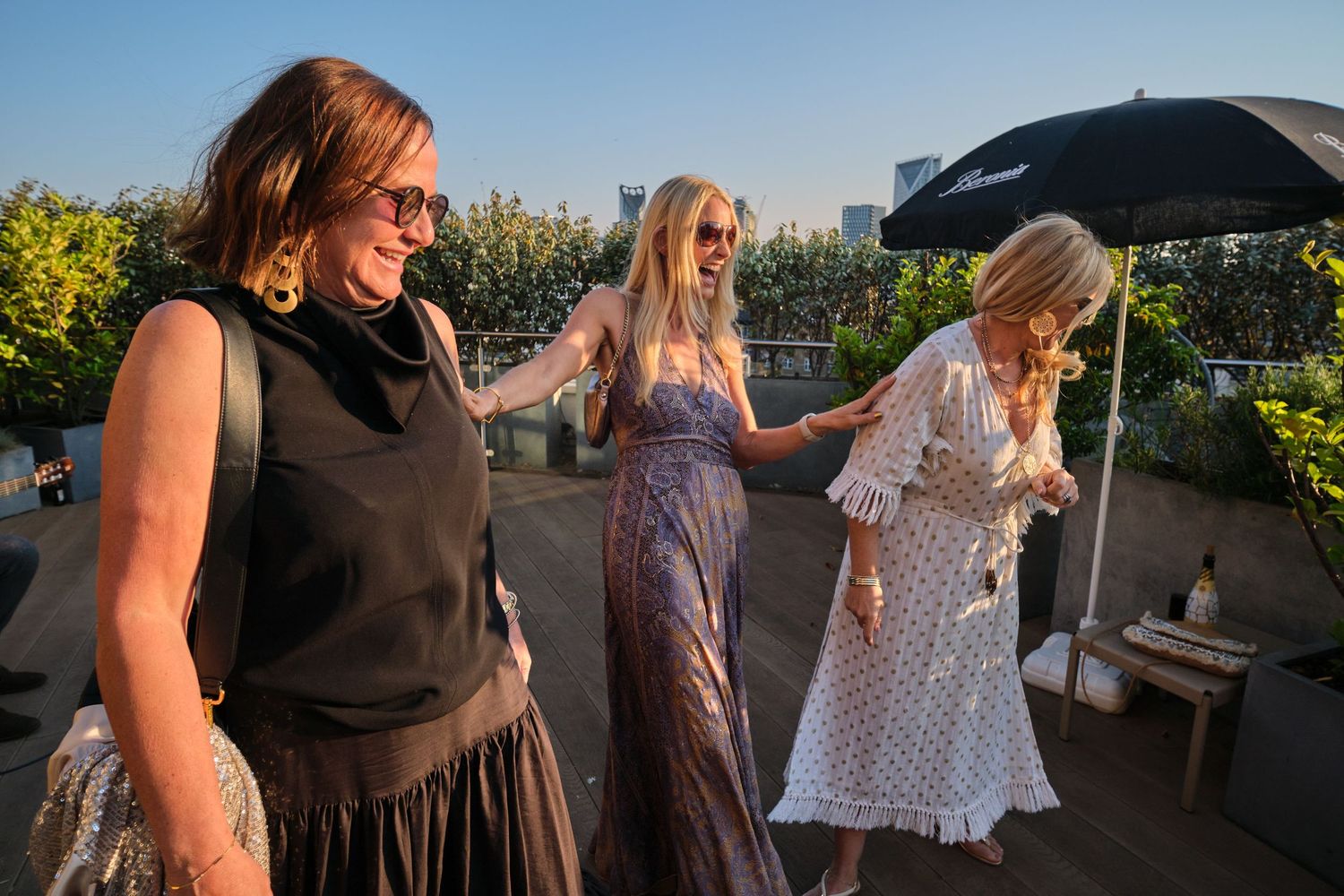 Outdoor celebration at sunset with people dancing and string lights creating a warm ambiance on a rooftop venue.