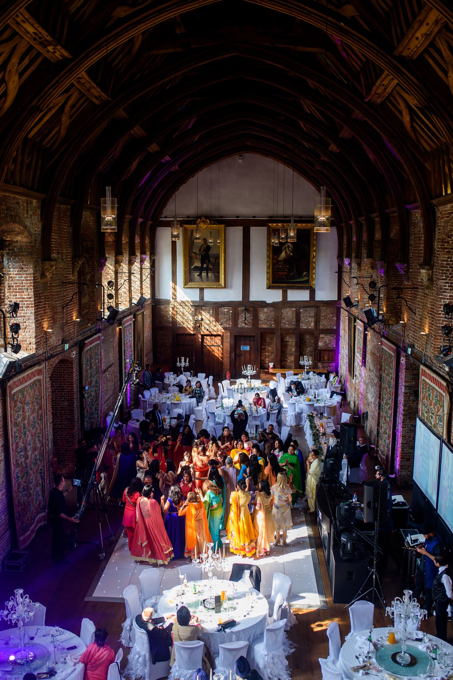 Grand hall wedding reception venue with elegant table settings and purple lighting.