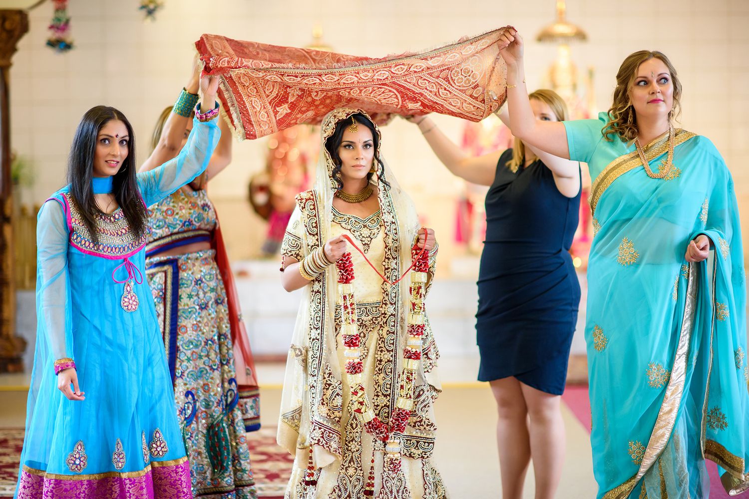 Group of wedding guests in vibrant blue and pink saris dancing together at reception.