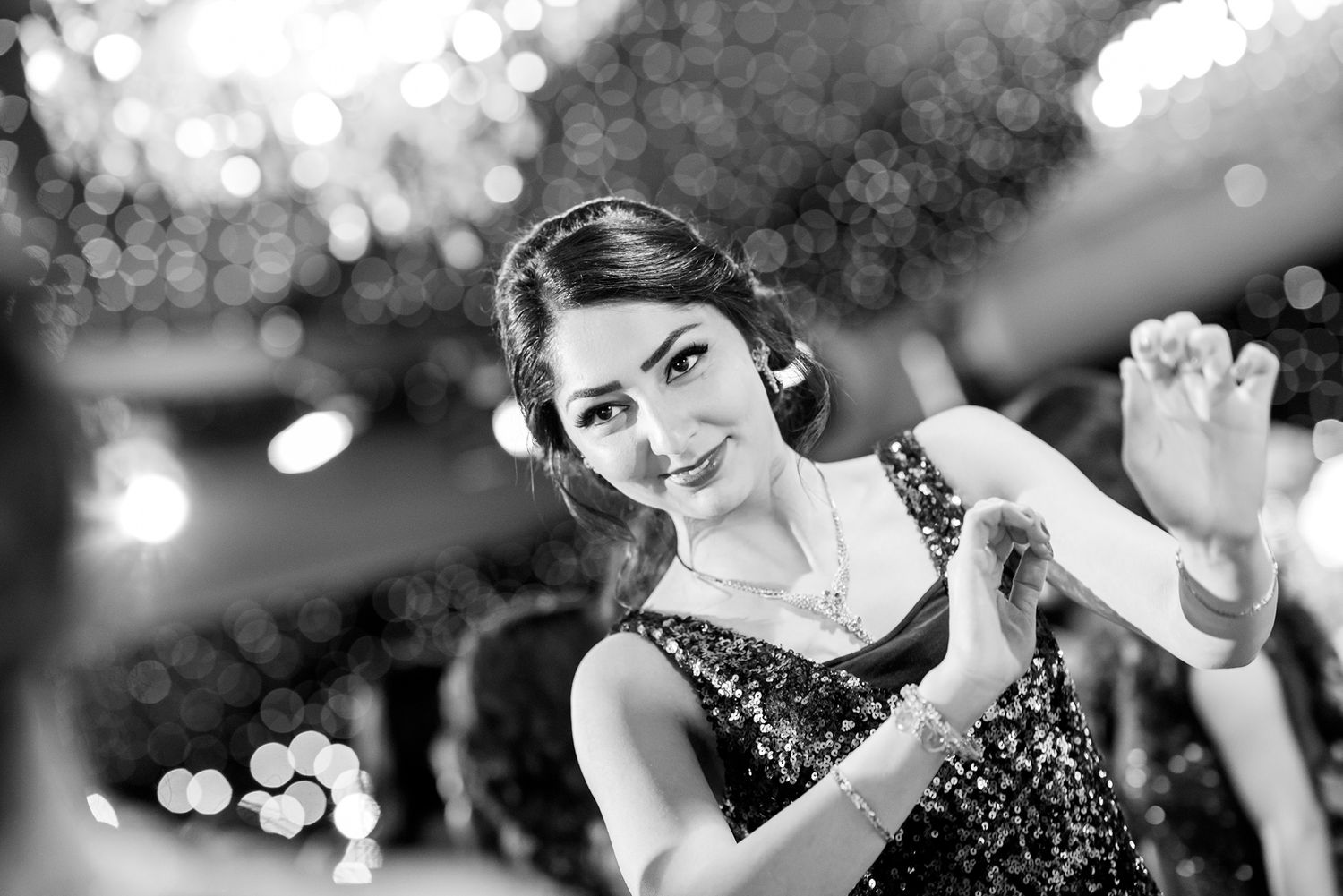 Black and white shot of elegant party with bokeh lighting effects and formal attire.