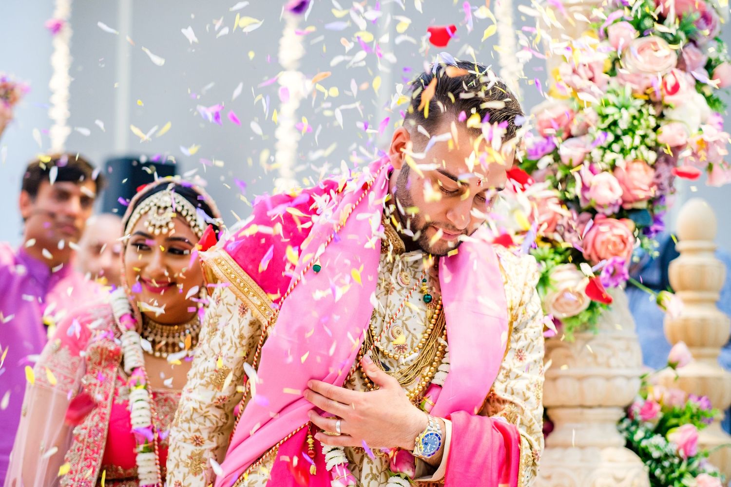 Celebratory moment with pink flower petals and confetti falling during an outdoor wedding ceremony.