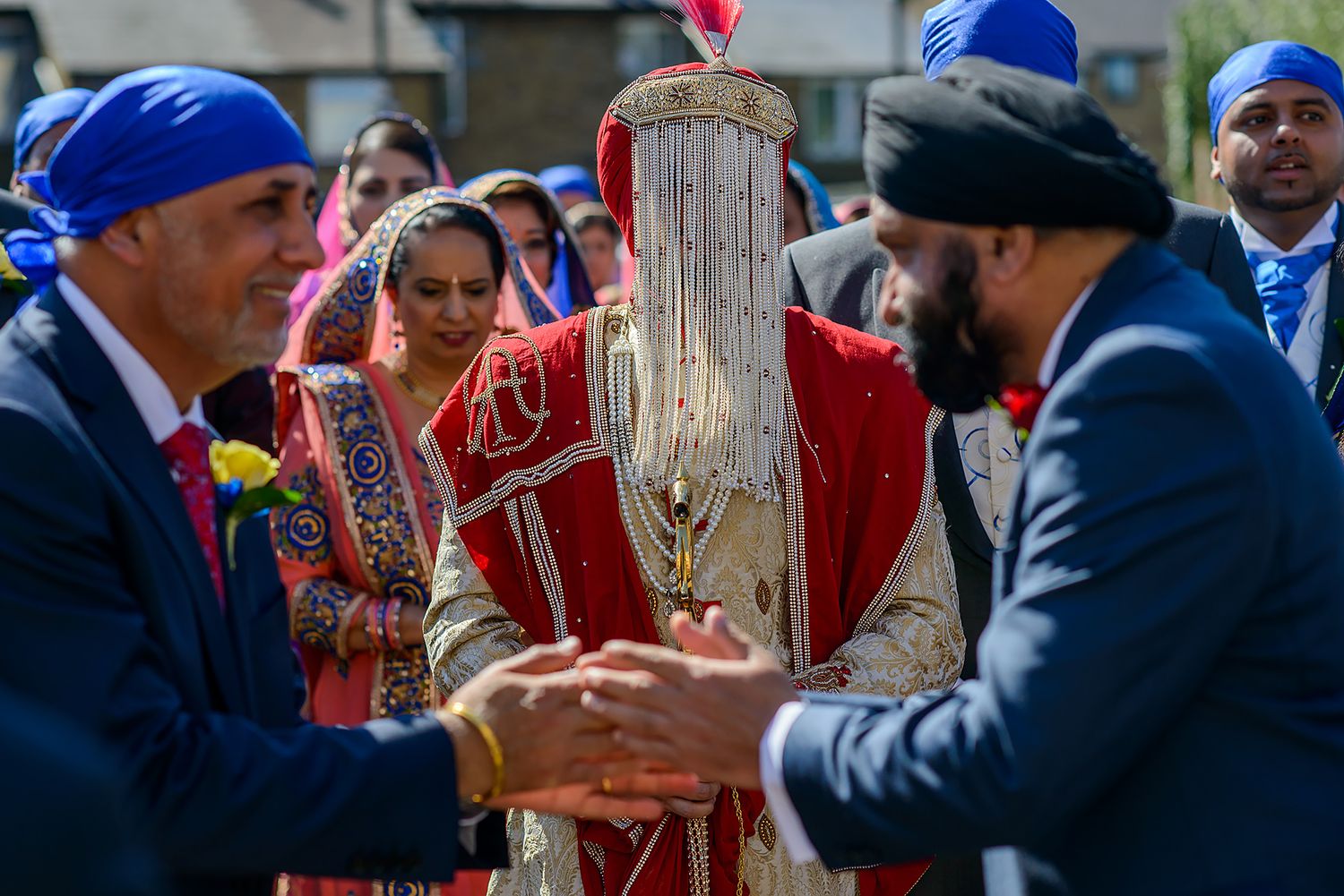 Guests in formal attire gather at outdoor wedding ceremony wearing blue and red accessories.