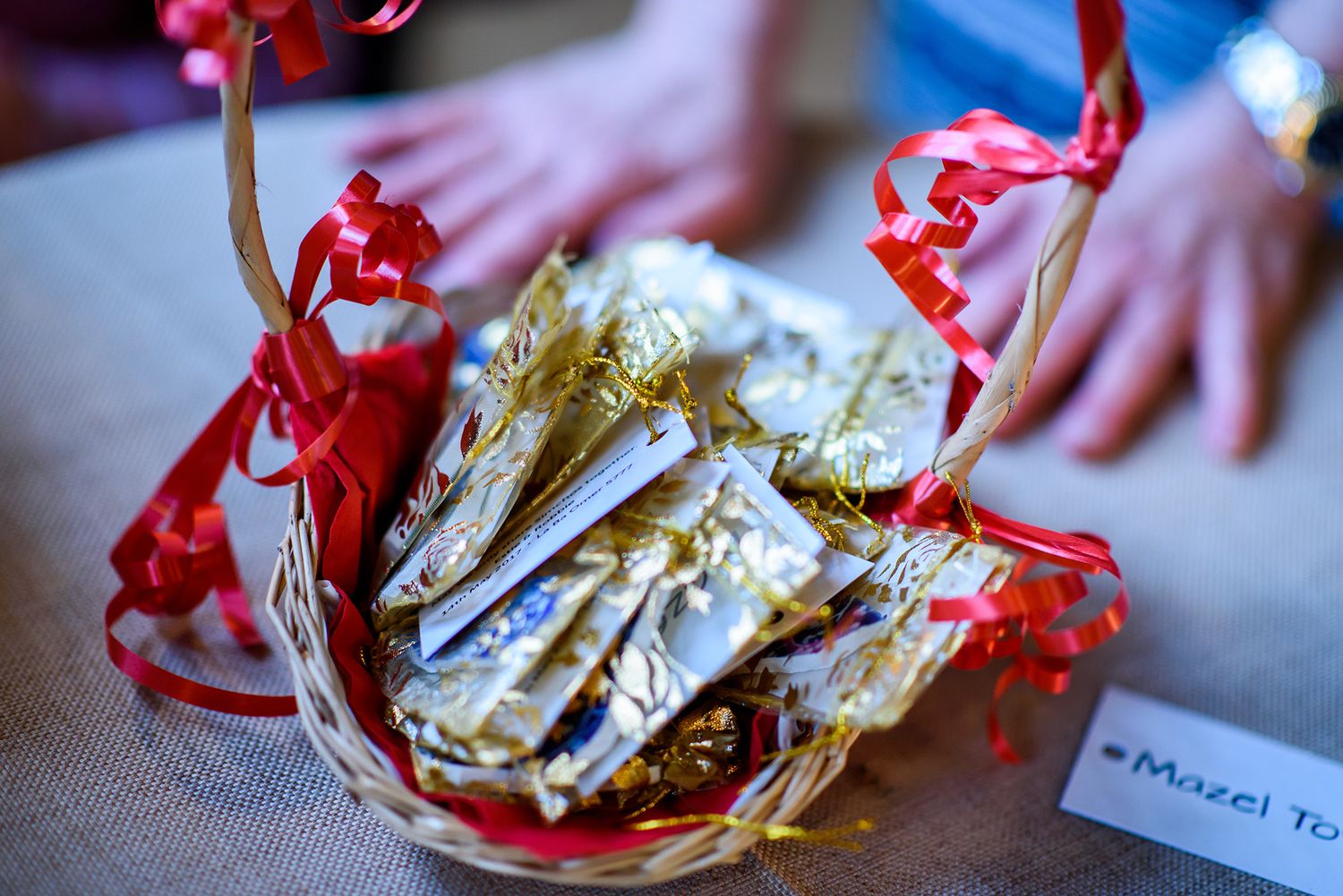 Wedding favors wrapped in gold foil with red ribbons displayed on a table.