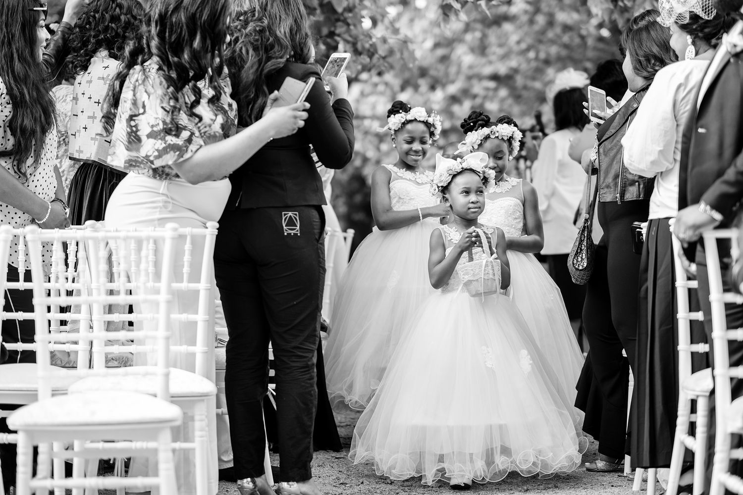 Elegant outdoor wedding ceremony setup with white chairs and natural greenery.