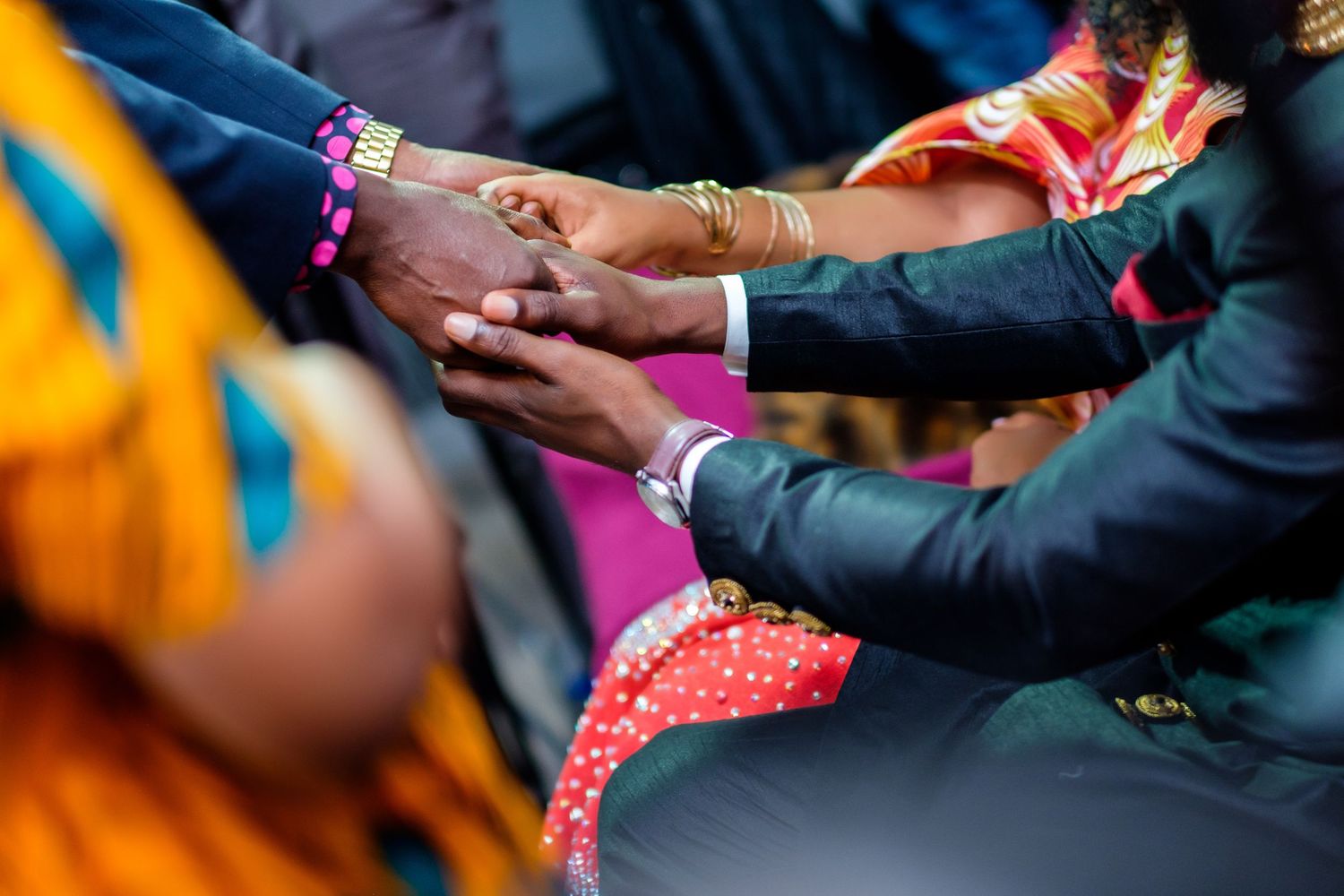 Wedding guests joining hands in a circle during an outdoor celebration.