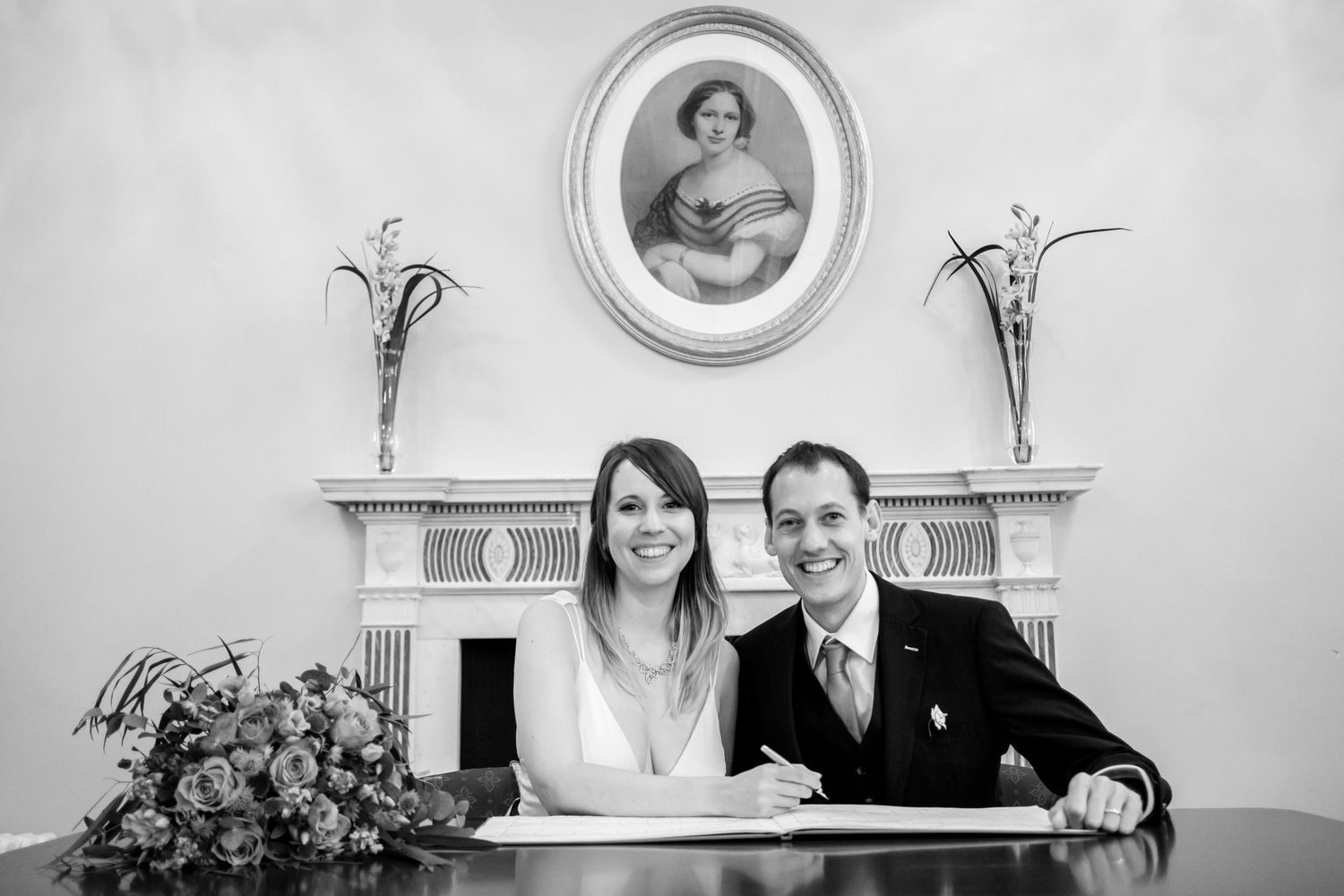 Black and white wedding photo capturing moments of celebration in an elegant indoor setting.
