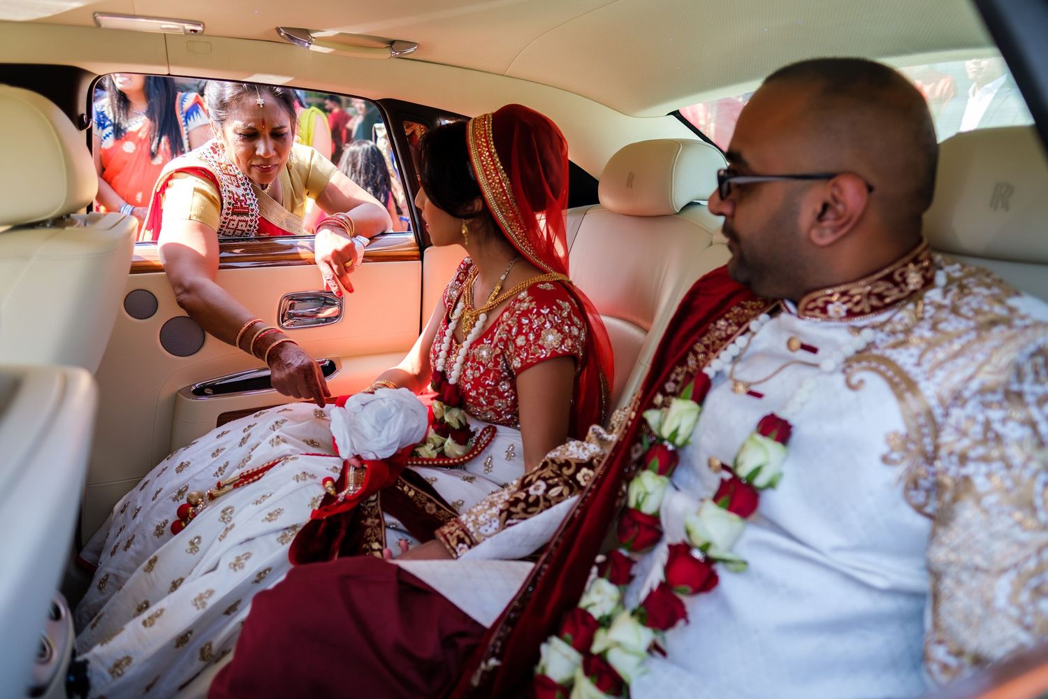 Wedding party members in formal attire seated at decorated reception tables.