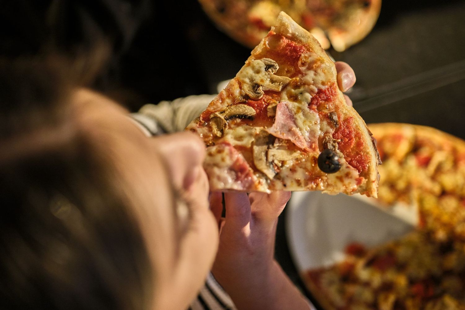 Close-up of fresh pizza being served with melted cheese stretching dramatically.
