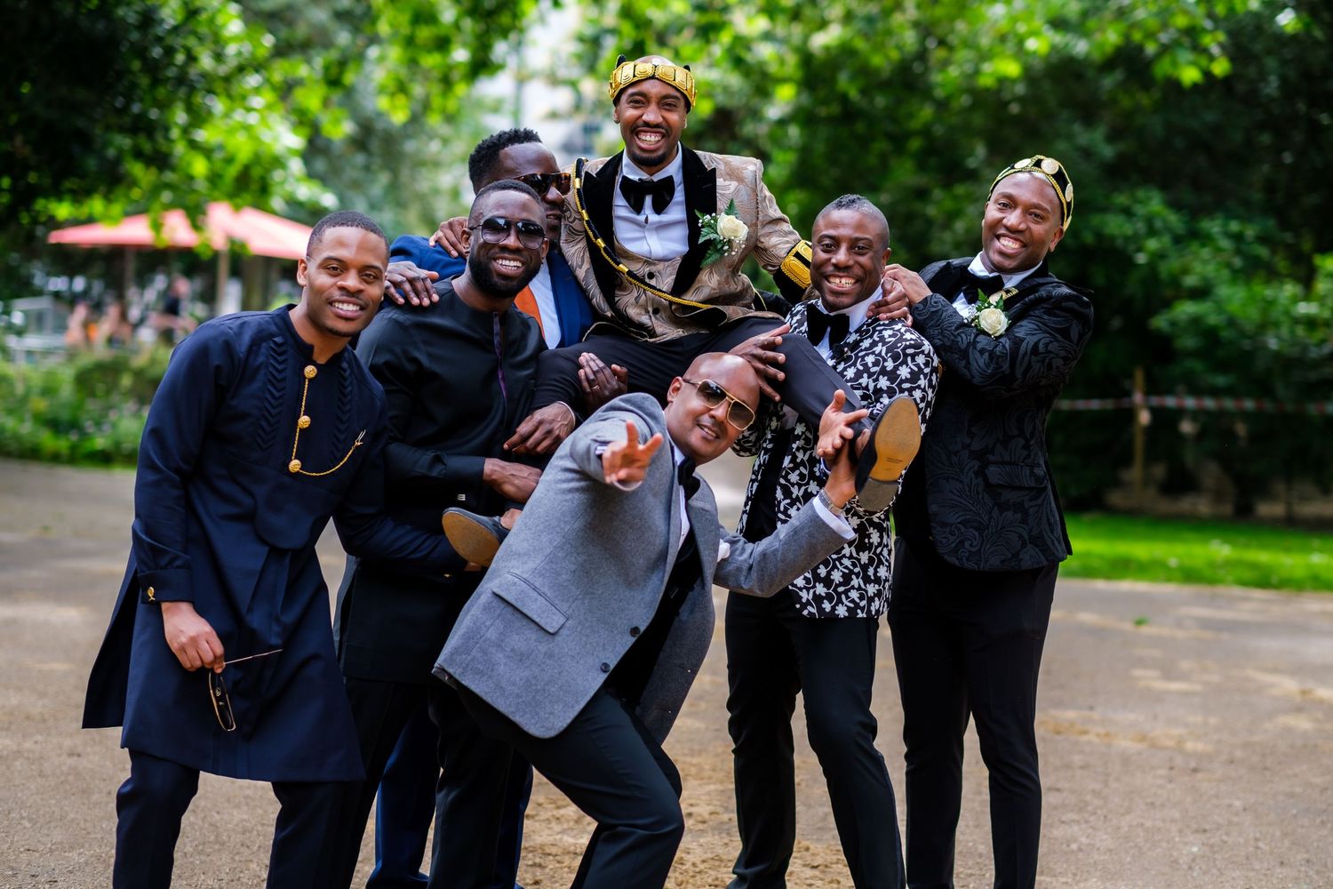 Wedding party poses playfully in a garden setting with dramatic expressions and casual poses.