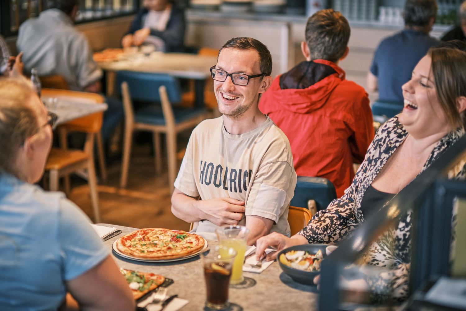 Friends enjoying pizza and conversation at a casual restaurant gathering.