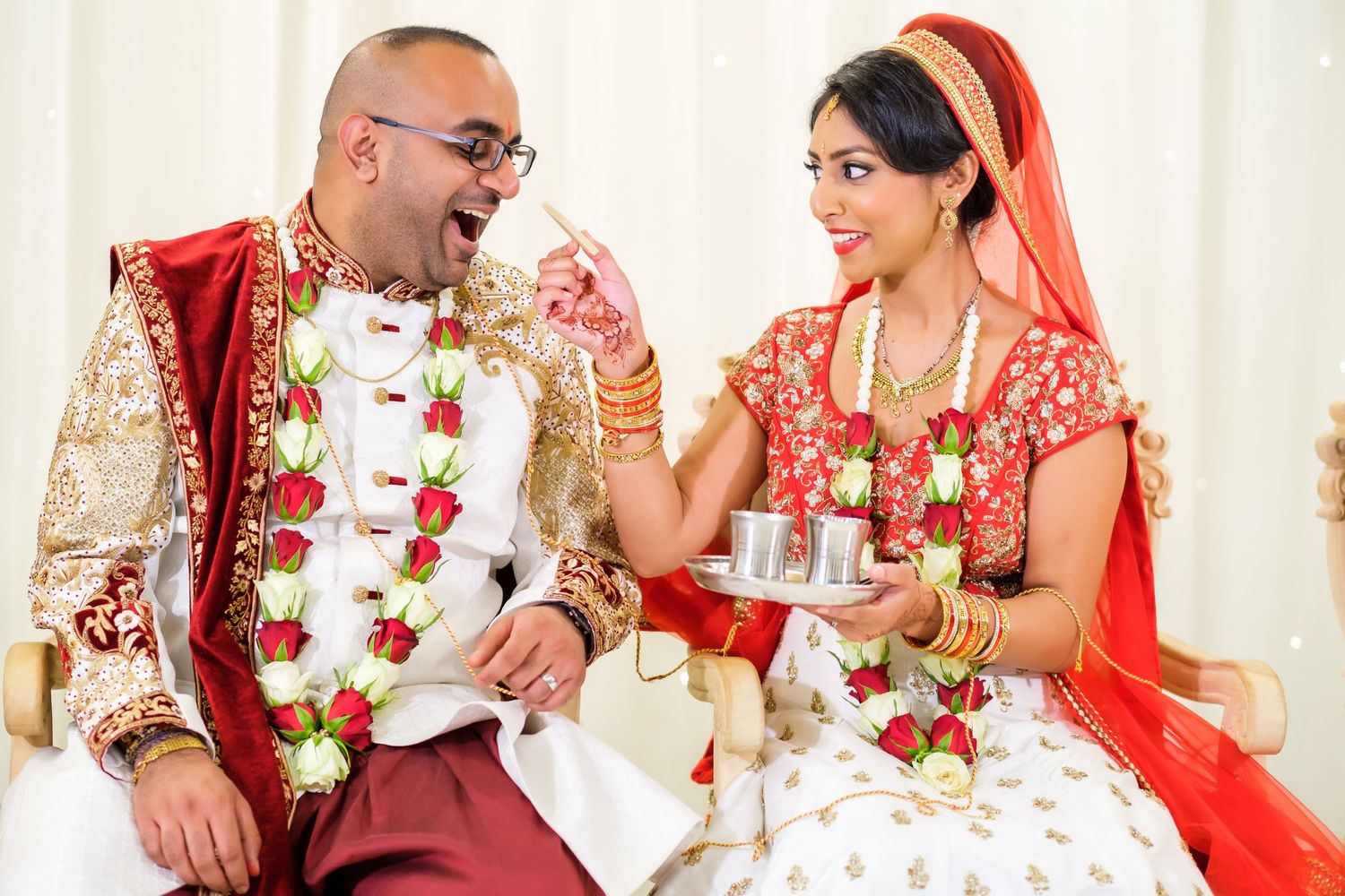 Couple in traditional Indian wedding attire during ceremony rituals.