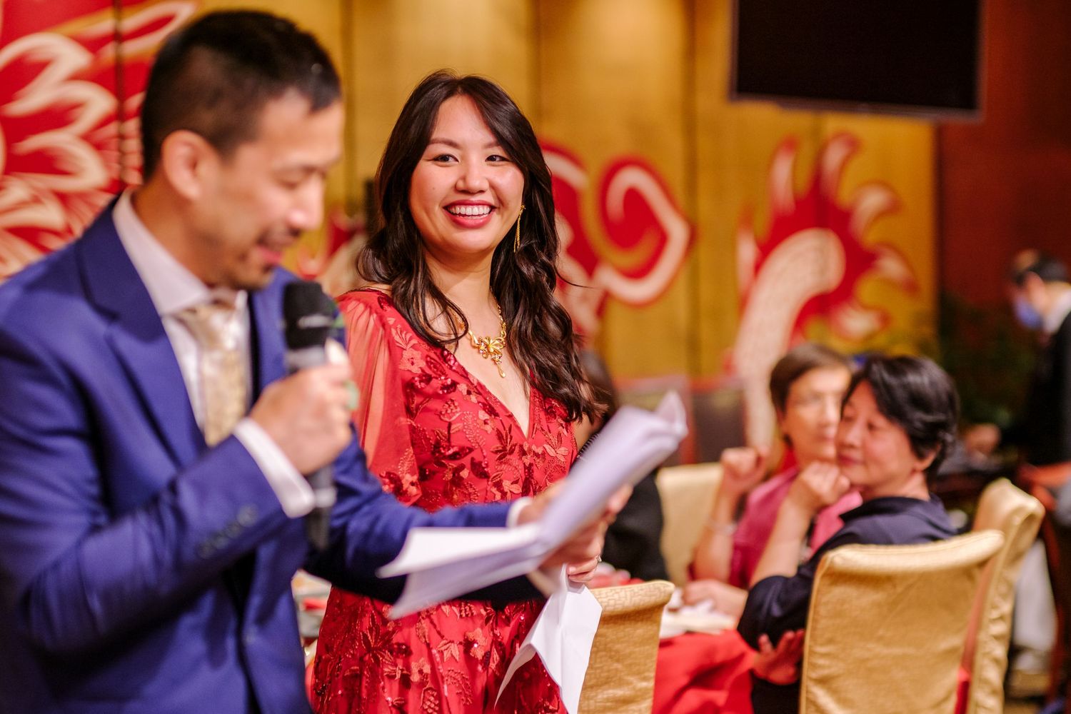 Wedding celebration in a reception hall with red and gold decor elements.