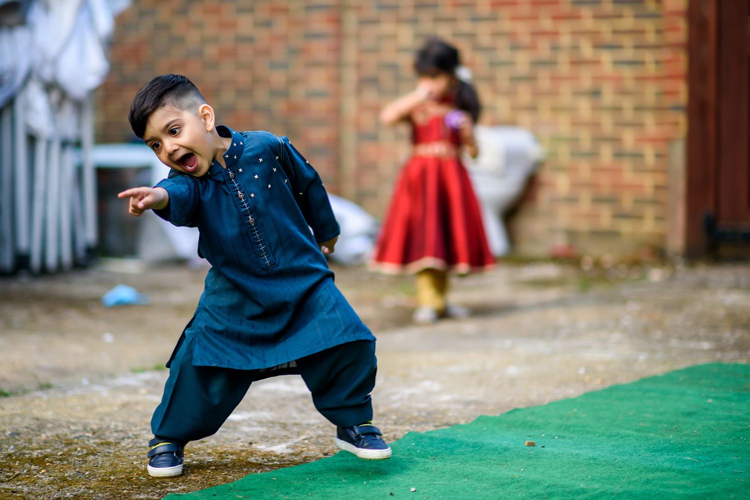 Young person in blue clothing plays on artificial grass turf outdoors.