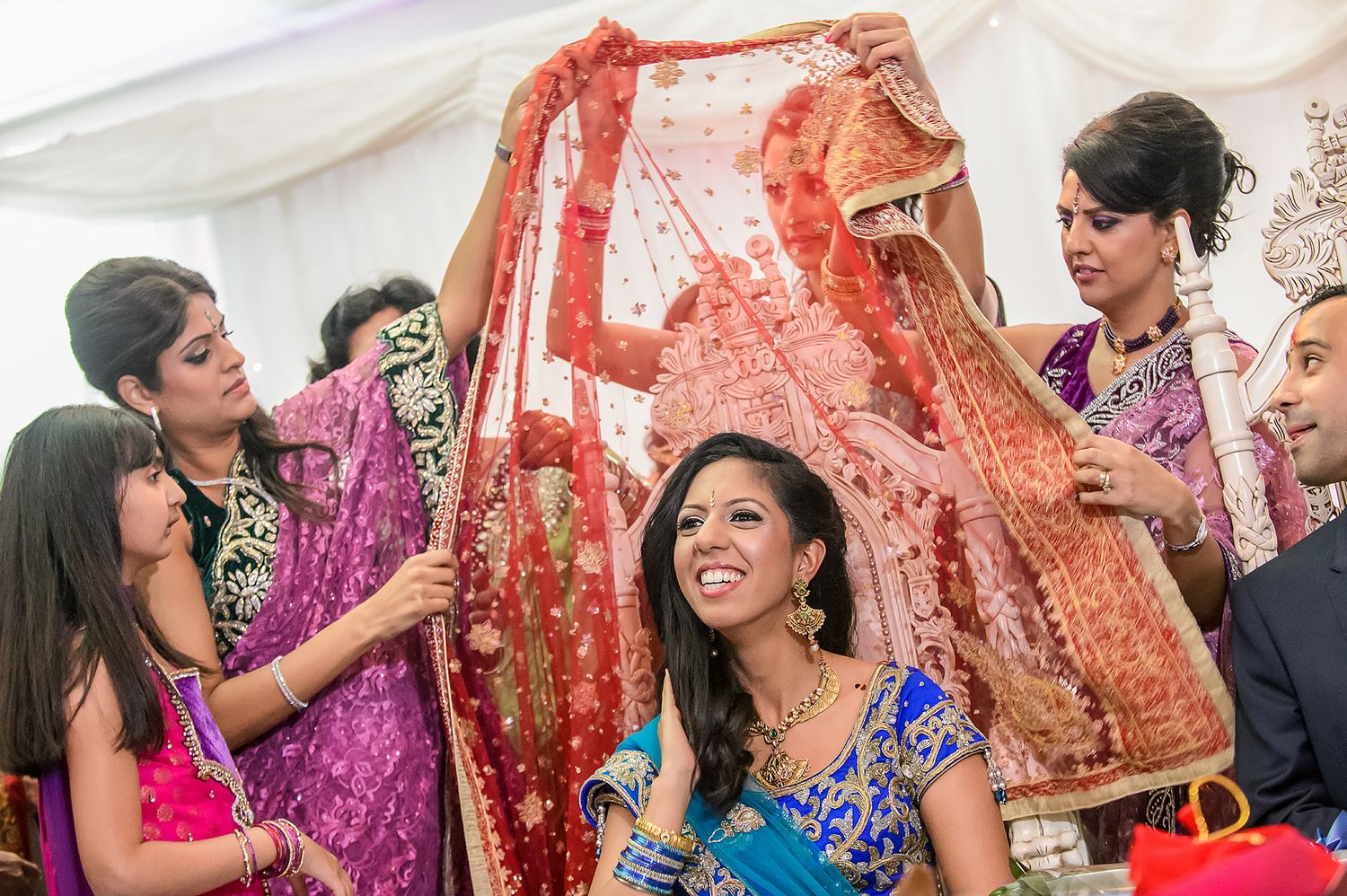 Festive moment with women in colorful saris celebrating during a traditional wedding ceremony.