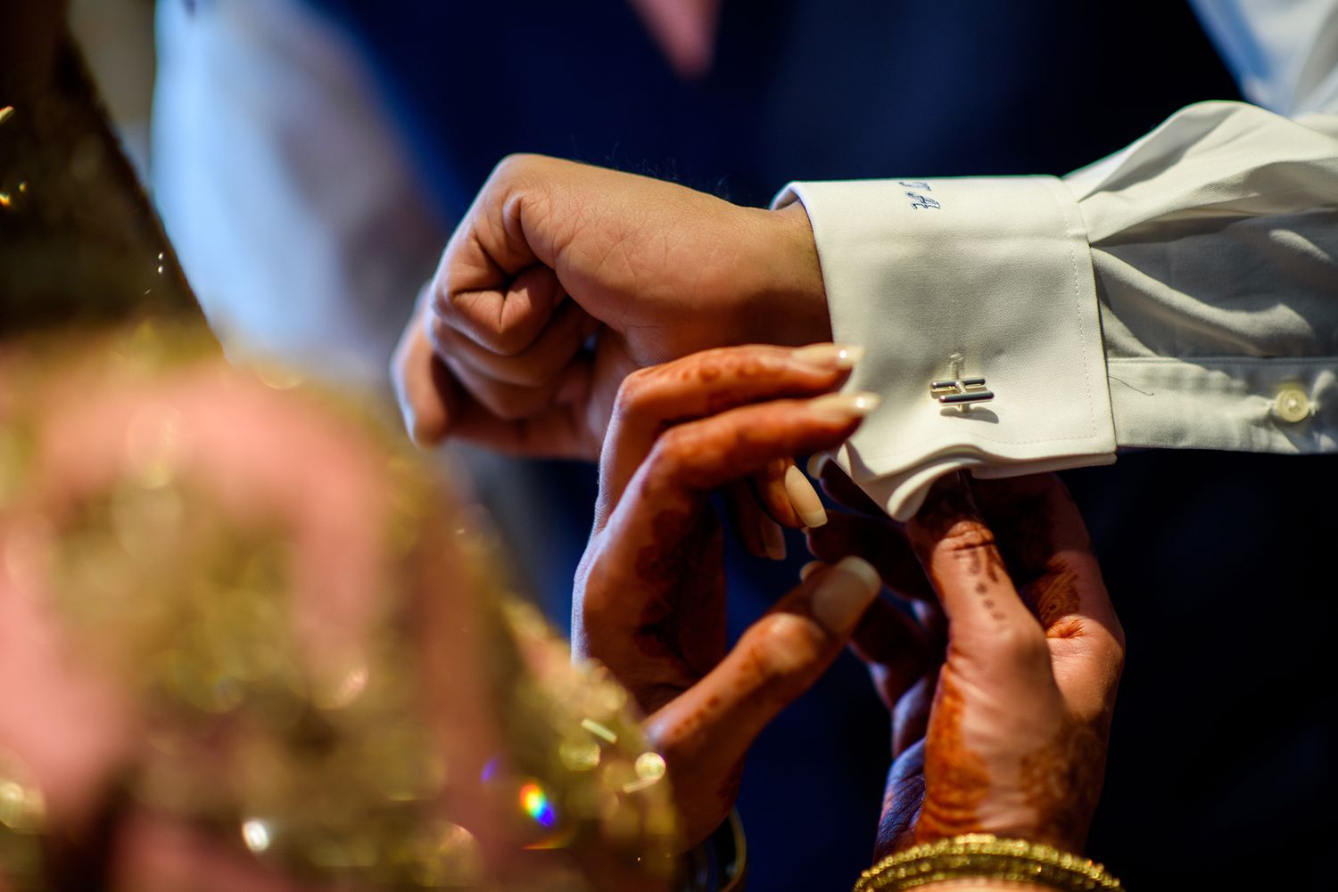 Ring being placed during an Indian wedding ceremony with henna decorated hands.