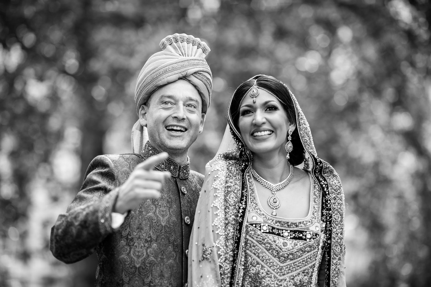 Black and white photo captures joyful wedding couple sharing a candid moment outdoors.