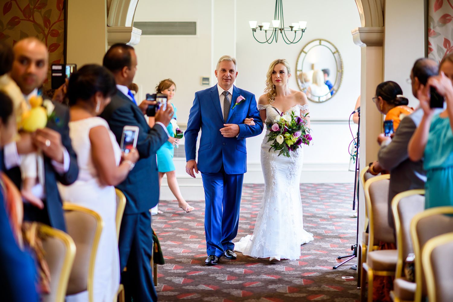 Wedding party attendees share joyful moments in an elegant venue with blue and white attire.