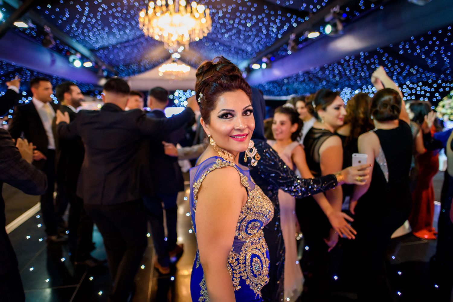 Glamorous wedding reception with crystal chandeliers and blue lighting effects.
