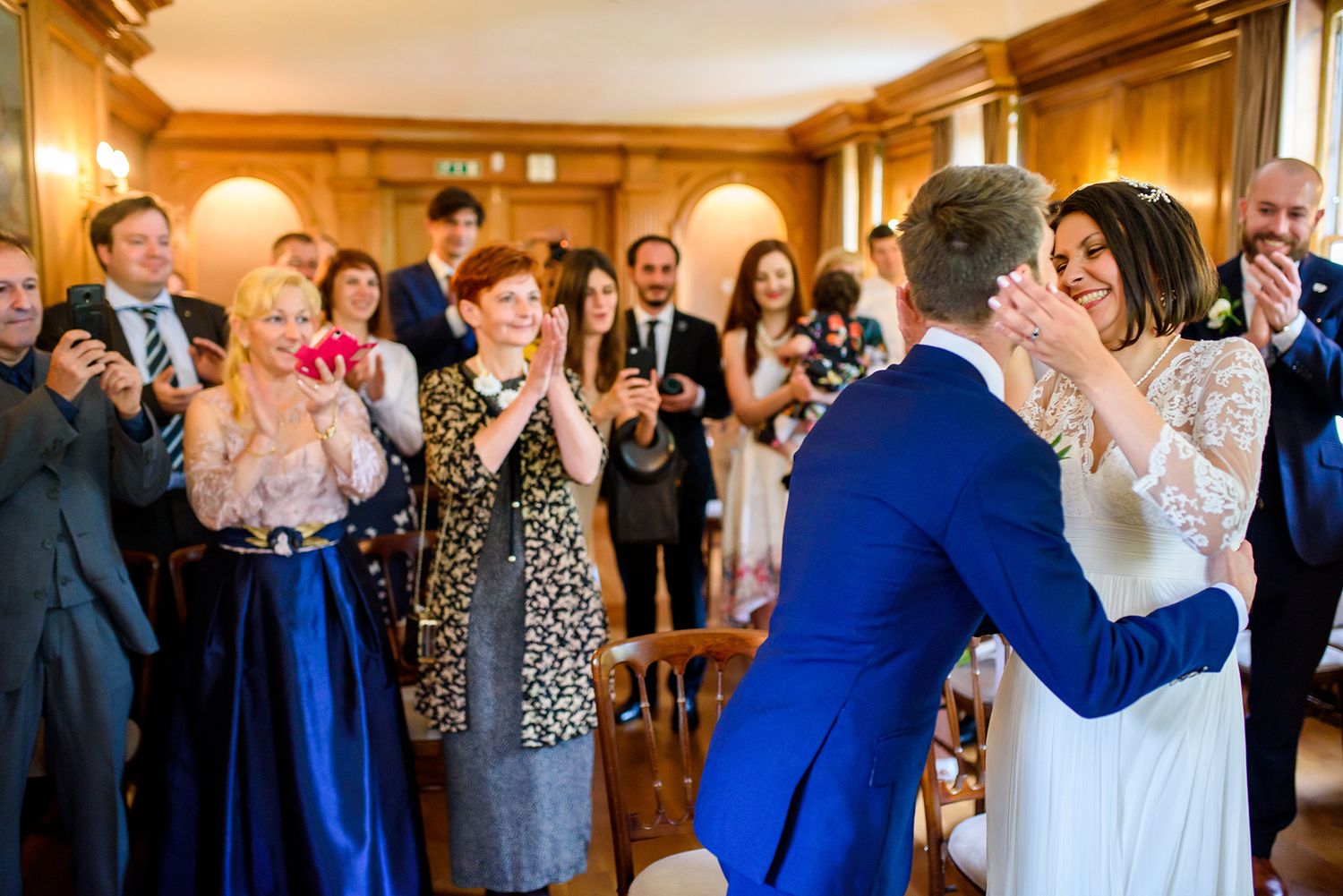 Wedding guests celebrate and applaud during reception in grand ballroom.