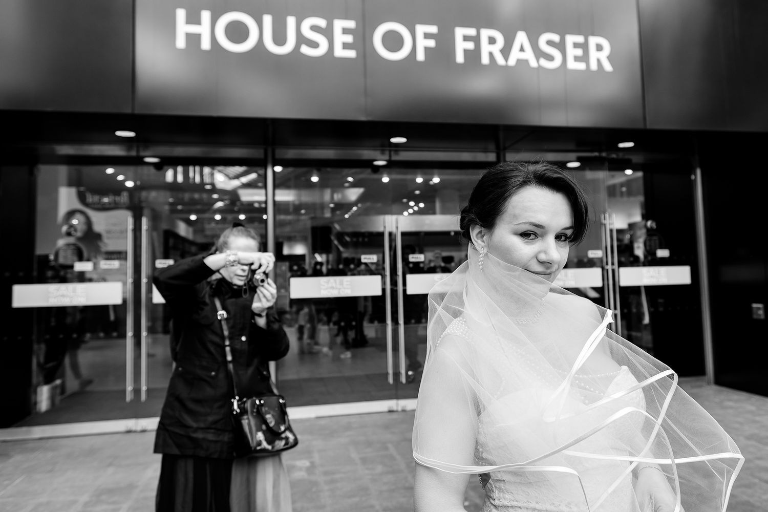 Black and white wedding photo outside House of Fraser department store.