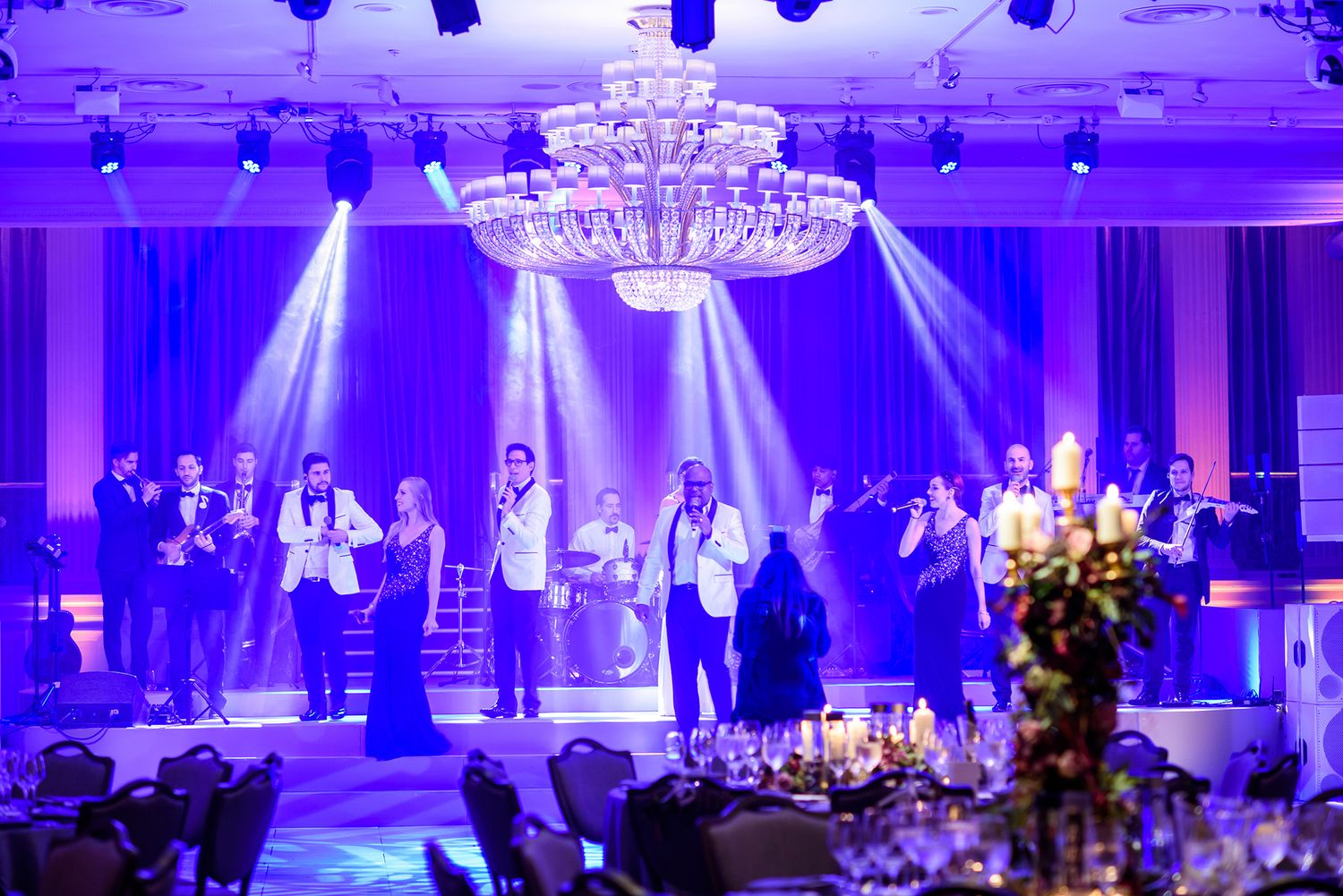 Spacious ballroom venue with theatrical lighting and crystal chandelier centerpiece.