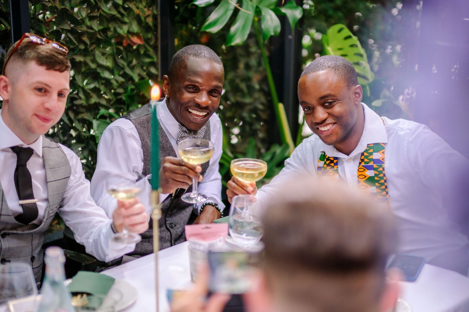 Wedding guests enjoying drinks and laughter at an outdoor reception.