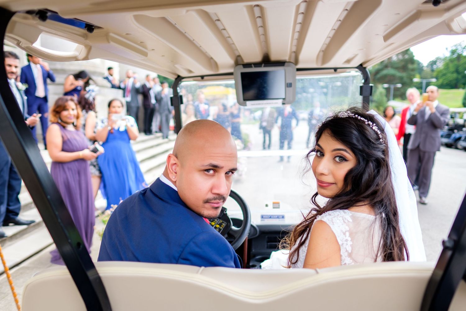 A couple sits in a golf cart during their wedding celebration.