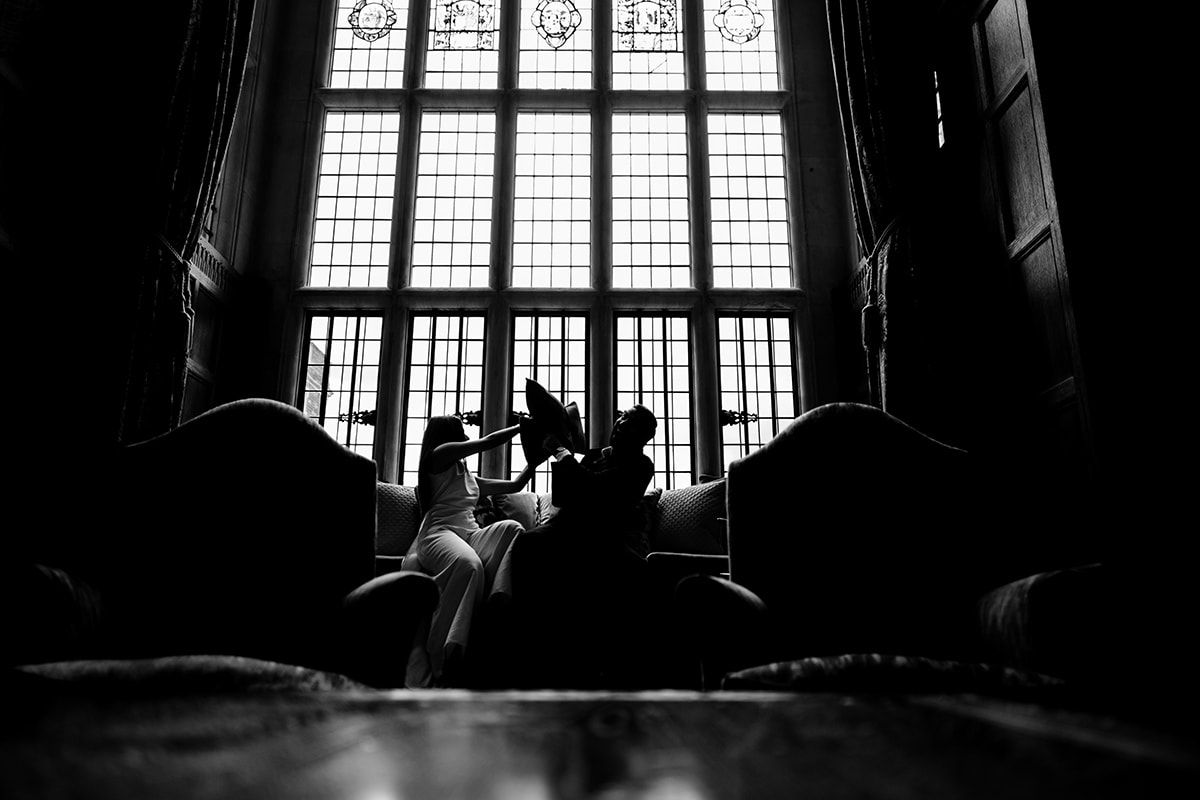 Dark silhouetted figures seen through ornate stained glass windows in vintage interior.