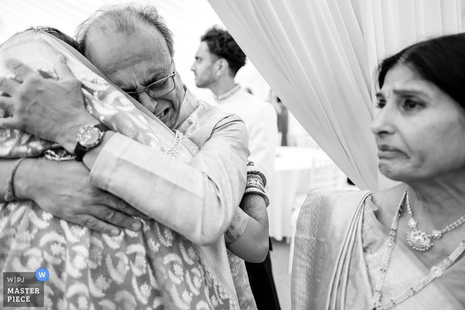 Black and white photo of guests celebrating during emotional wedding ceremony moment.