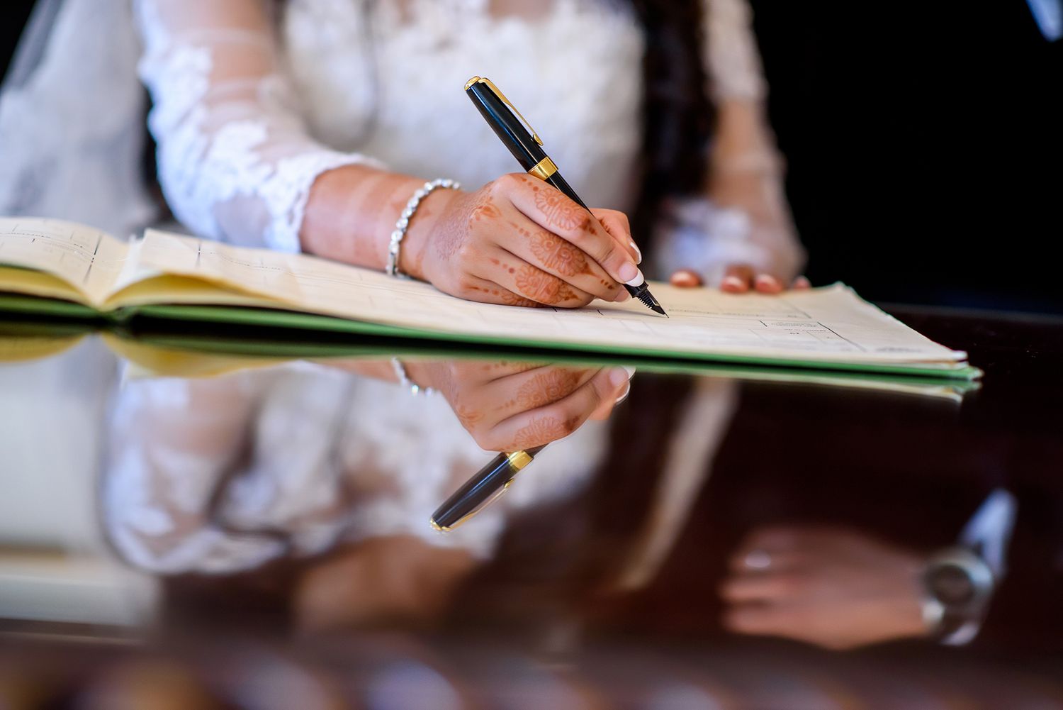 Close-up of hands signing documents with pen at a formal event.