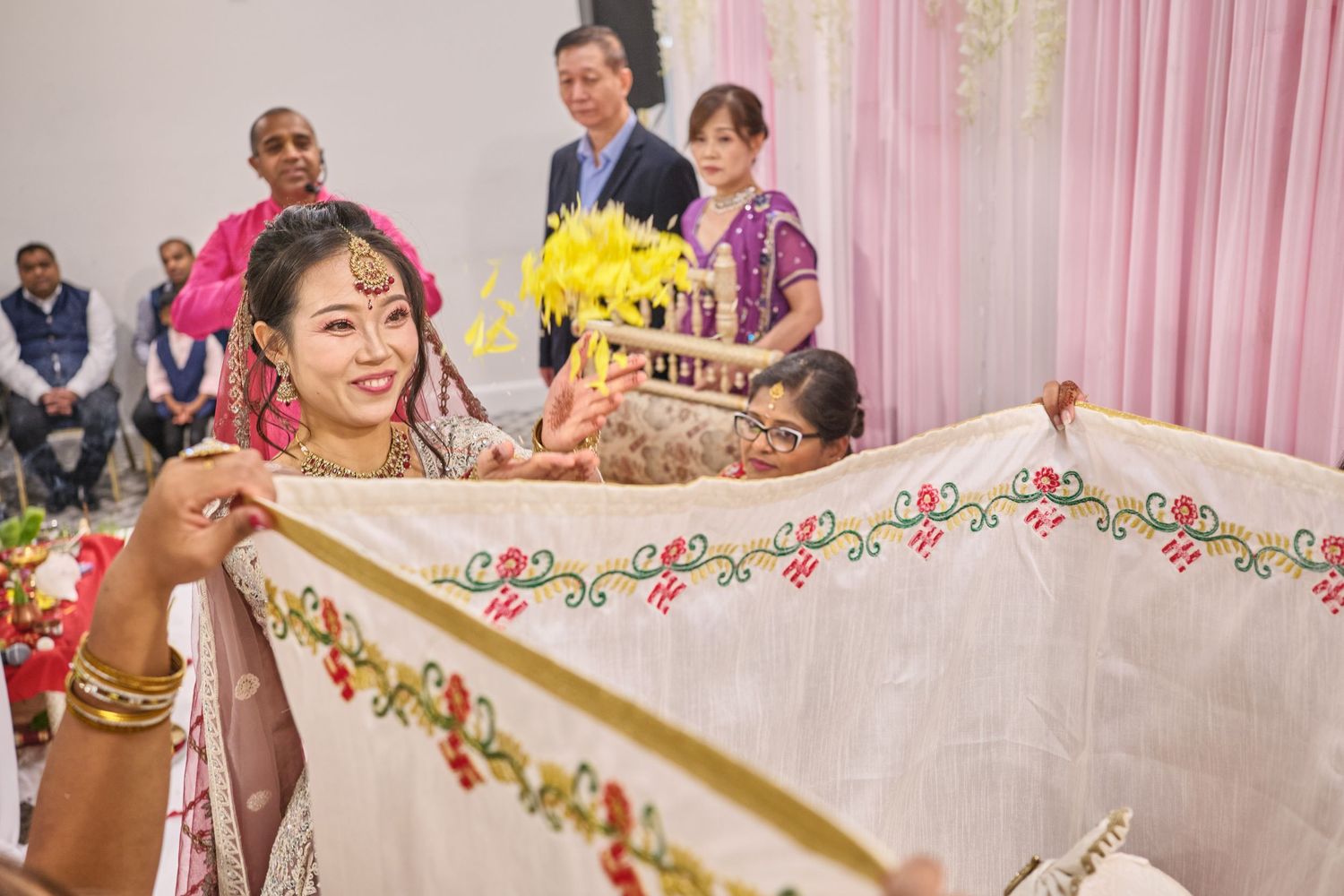 Pink and white decorated wedding venue with floral garlands and fabric draping.