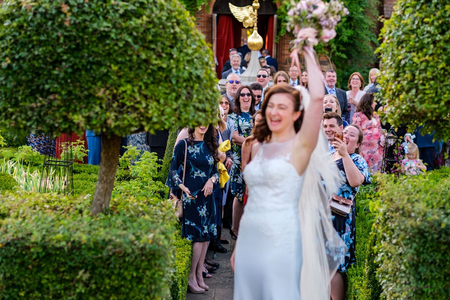 Garden wedding ceremony with guests gathered among lush greenery.