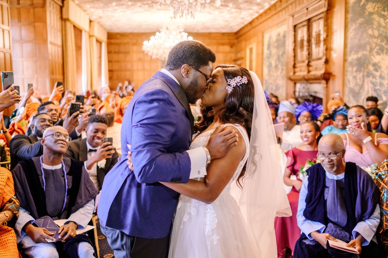 Wedding guests share joyful reactions during an emotional moment at an elegant indoor reception venue.