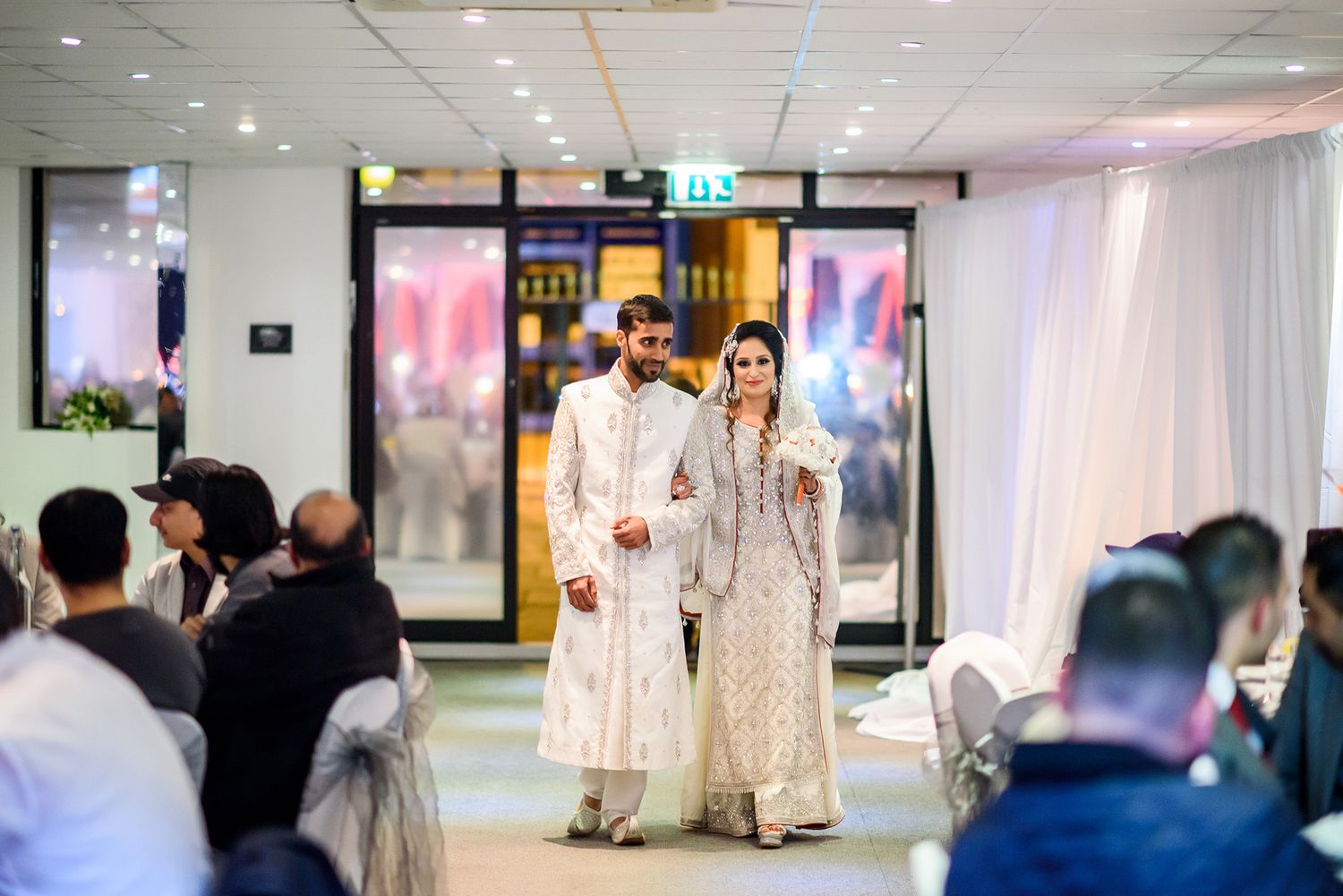 Wedding venue interior with elegant white decor and ambient lighting.