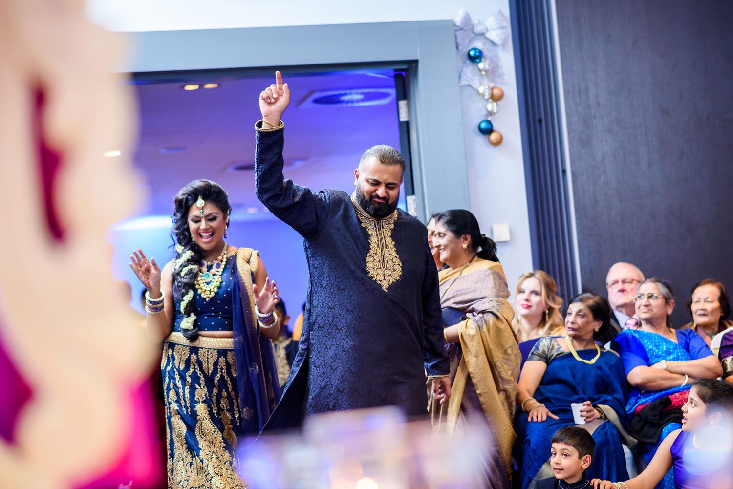 Guests celebrating with raised hands under blue ambient lighting at an indoor event.