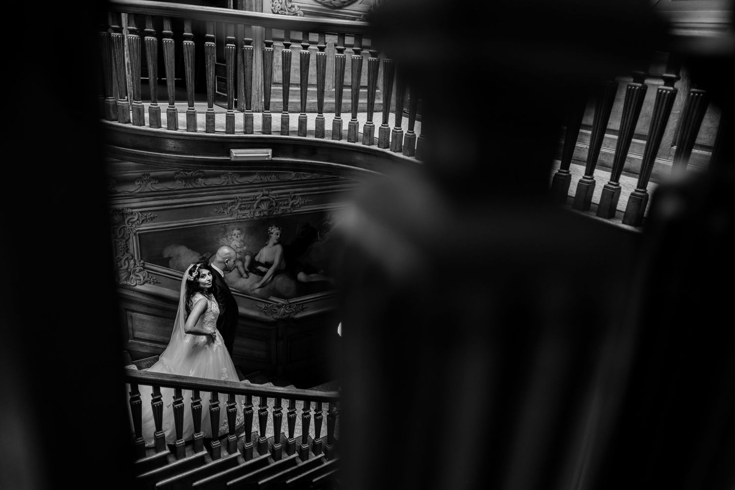 Artistic black and white photo of a wedding couple on an elegant staircase.