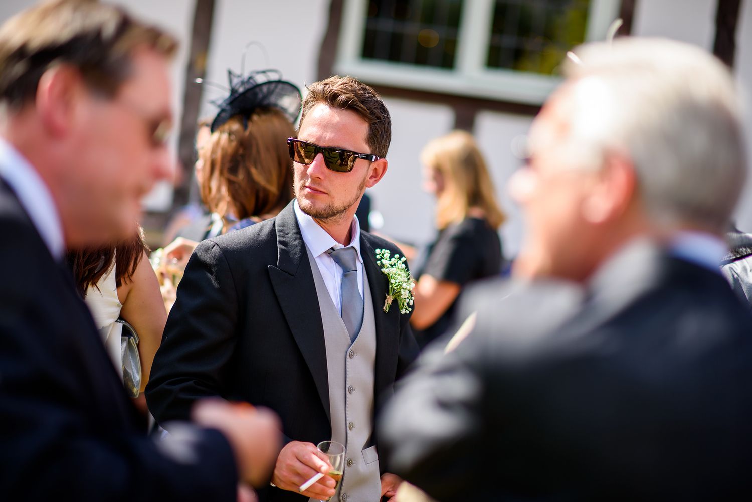 Wedding guests enjoy a celebratory moment outdoors during a sunny afternoon reception.