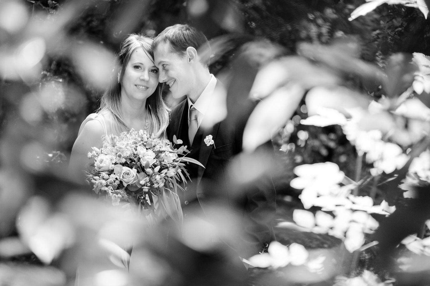 Dreamy black and white portrait with soft bokeh effects through trees.