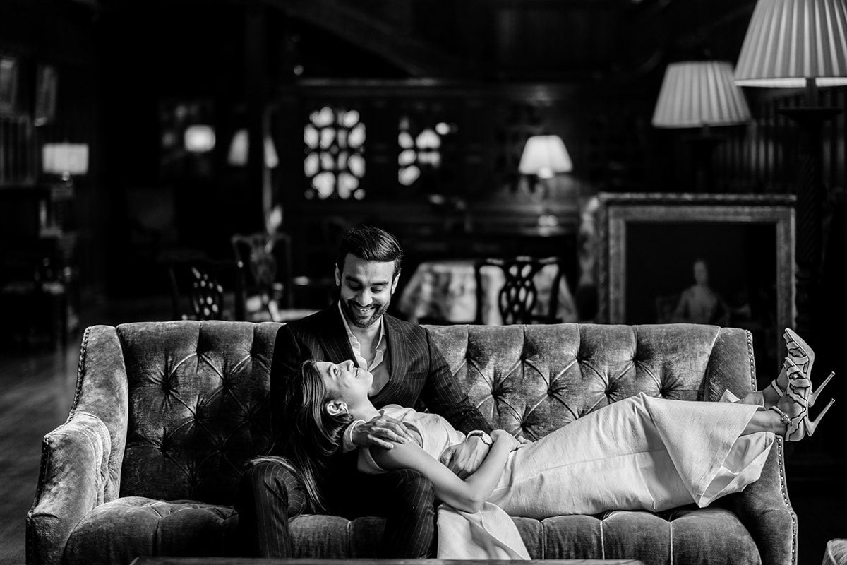 Couple relaxes on elegant tufted sofa in luxurious vintage room setting.