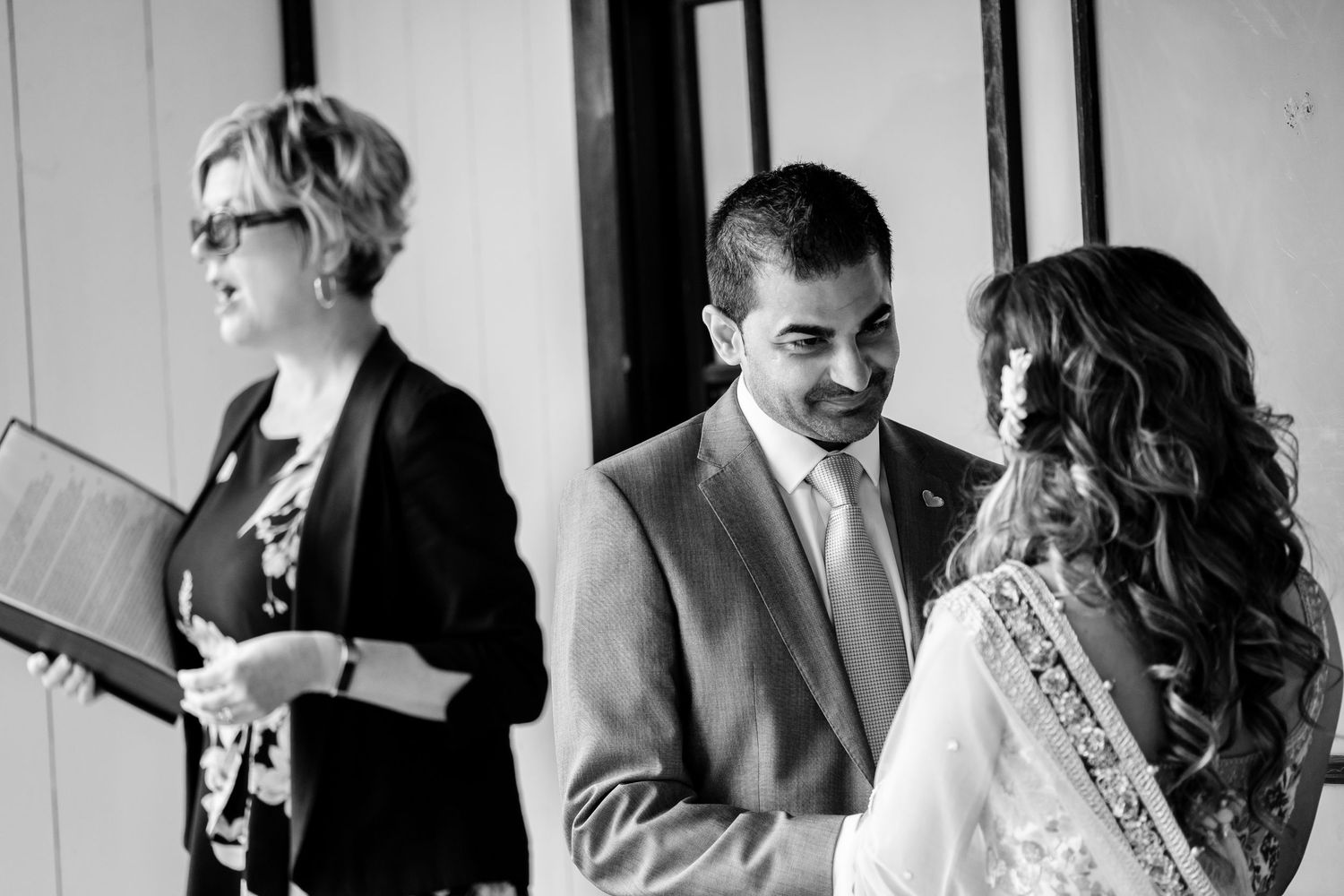 Black and white photo capturing intimate moments during an outdoor wedding ceremony.