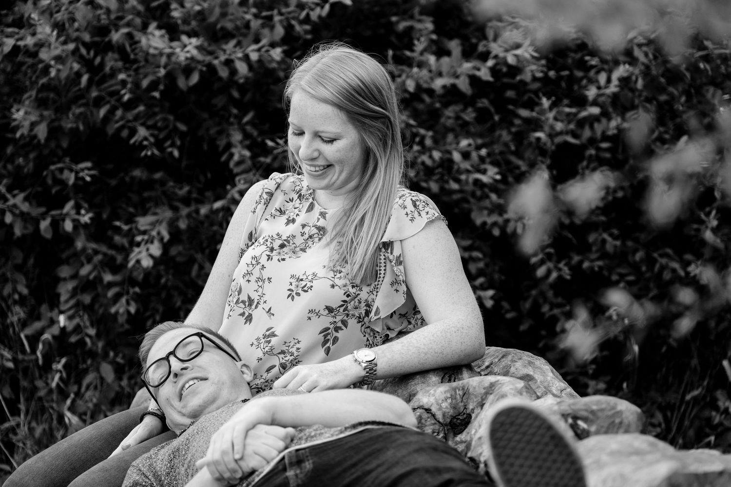 Black and white portrait of a couple sharing intimate moments in a garden setting.